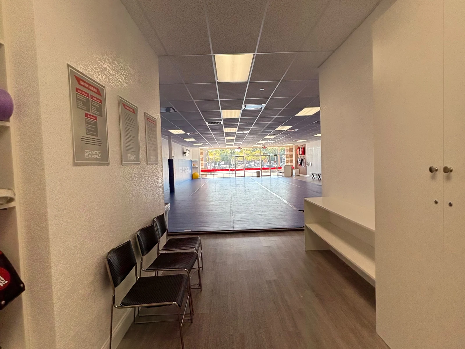 Hallway with chairs and cubbies looking out toward the mats and front windows of Gracie Barra Coppell